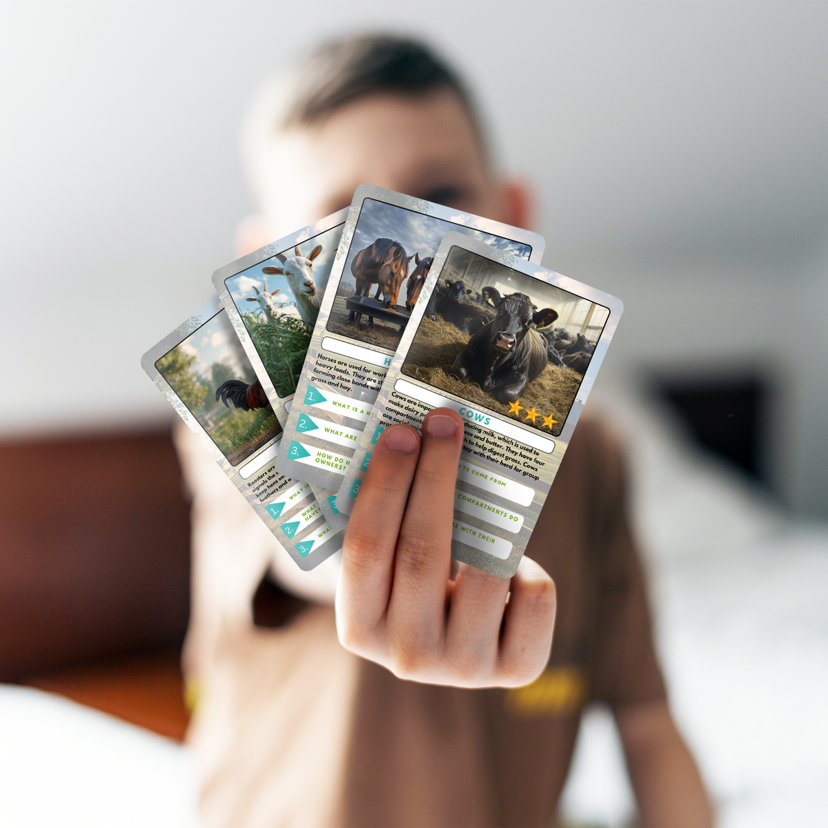 Hand holding trading cards with farm animal images against a blurred background