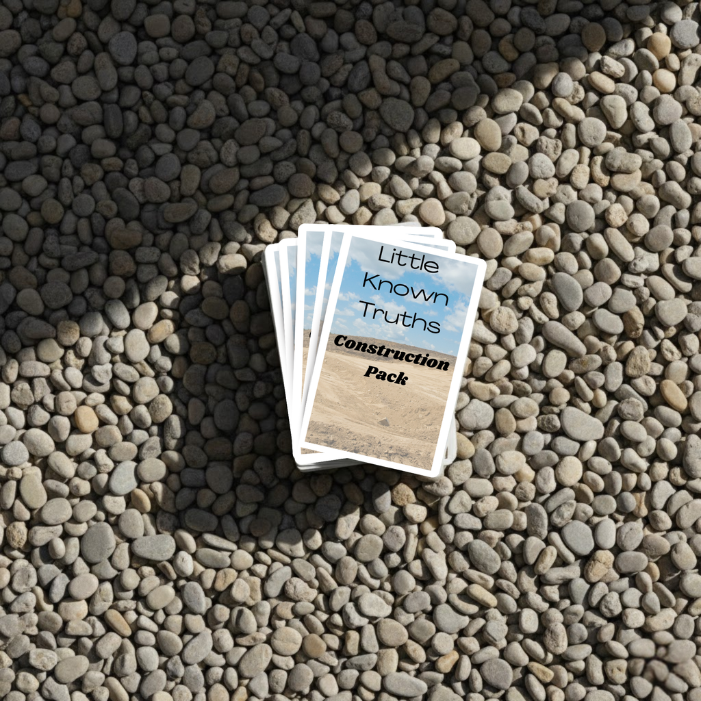 Card pack titled 'Little Known Truths Construction Pack' on pebbles
