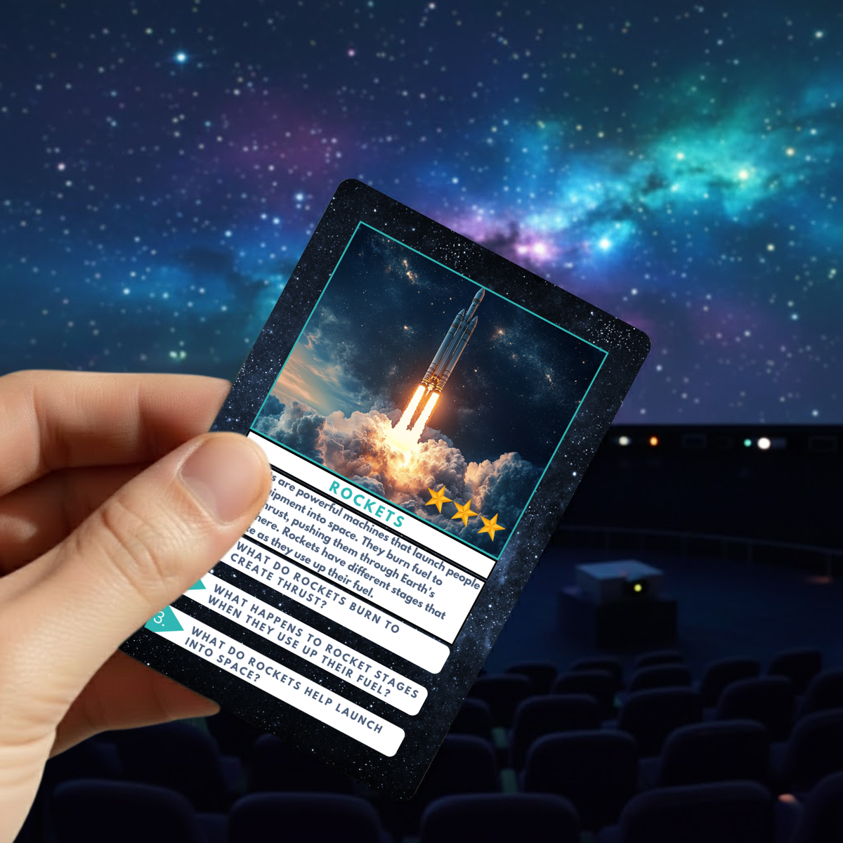 Hand holding a card with a rocket launch image within a planetarium.